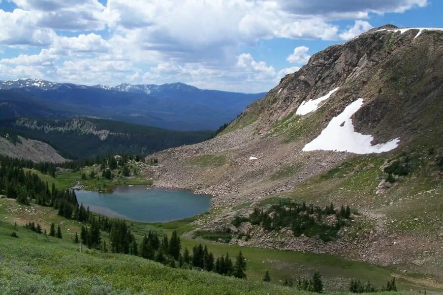 A mountain with a few snow patches left and a lake at the foot of it