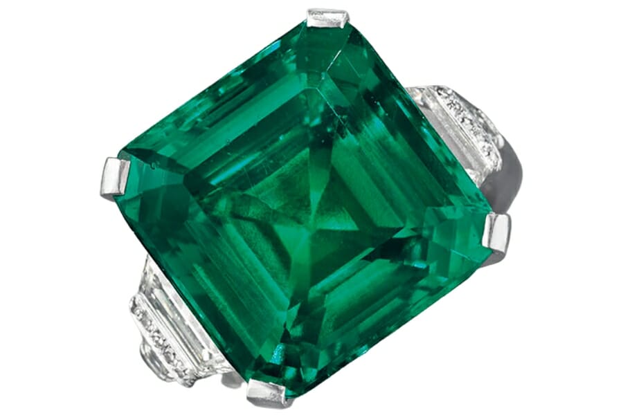 Beautiful, deep green Rockefeller emerald set on a ring with diamonds on the side
