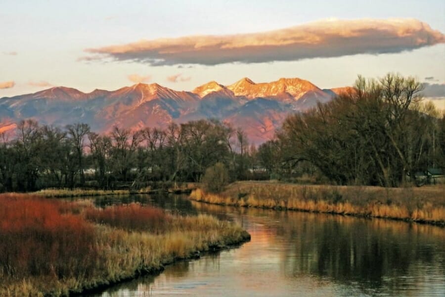 The San Luis Valley landscape with a river and trees surrounding it