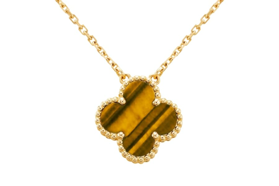 An expensive tiger's eye clover pendant surrounded by little crystals with a gold chain necklace
