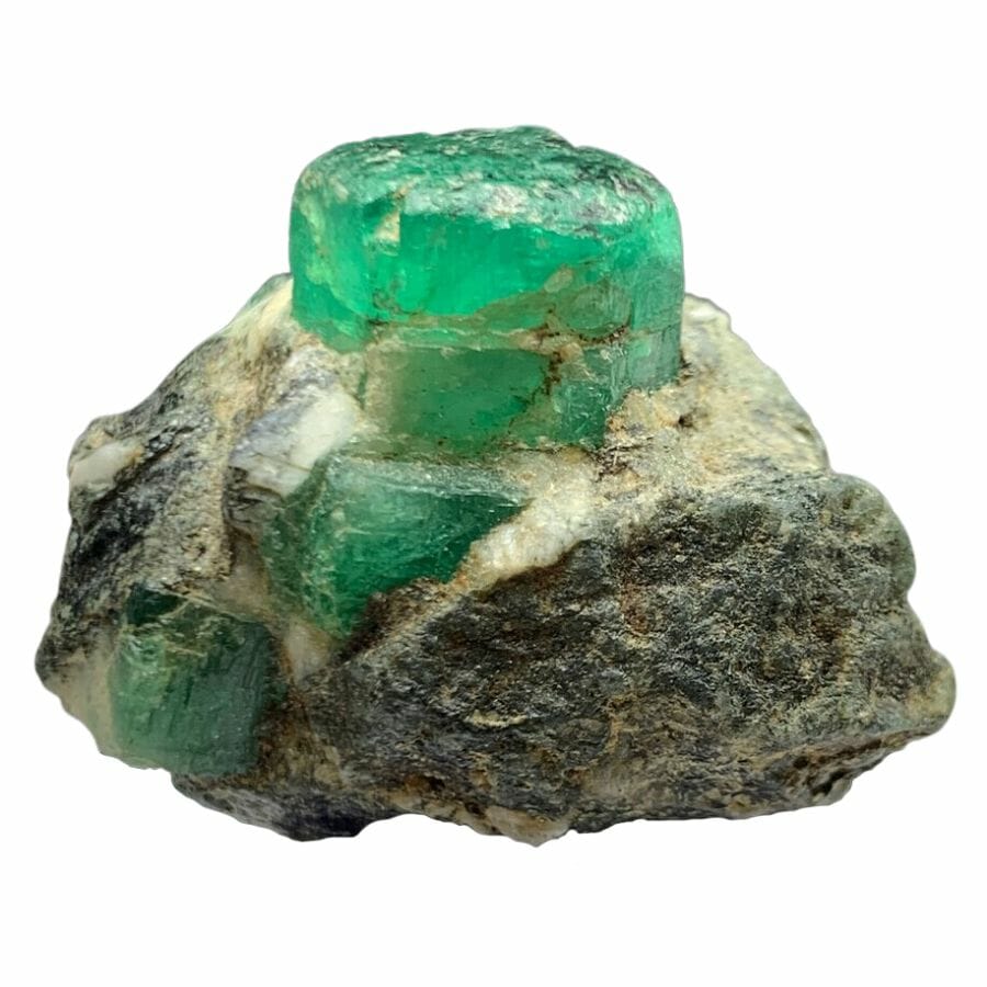 three bright green rough emerald crystals in rock
