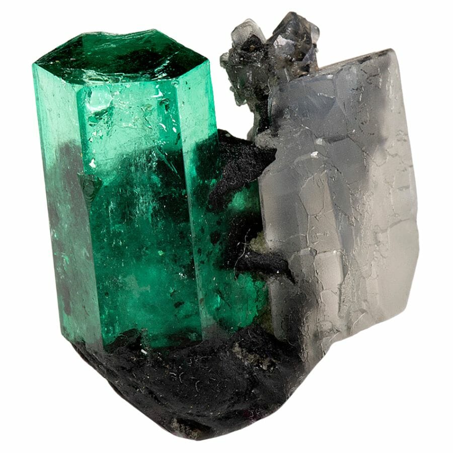 raw translucent green emerald crystal shaped like a six-sided prism, with calcite