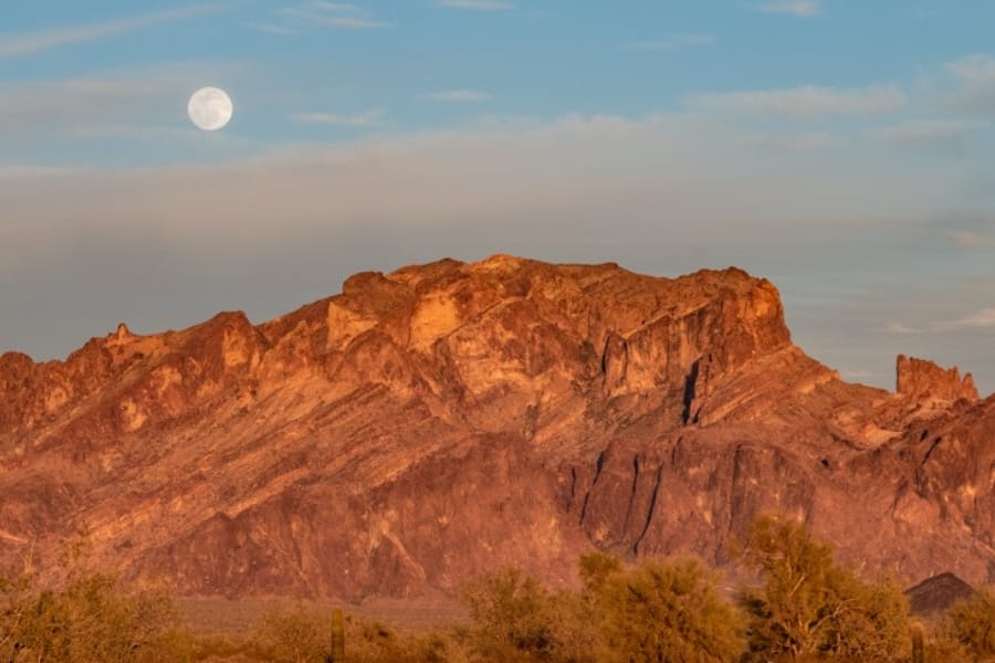 A breathtaking view of the Castle Dome Mountain with the moon peaking at the skies above it