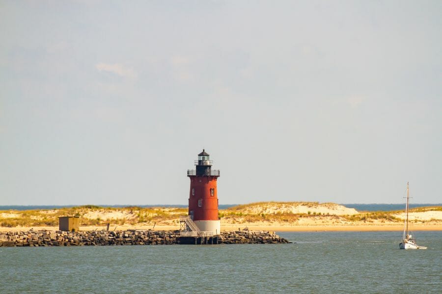 red light house with a white base on the shore