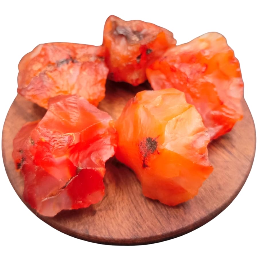 Five specimens of raw carnelian on a wooden circular plate