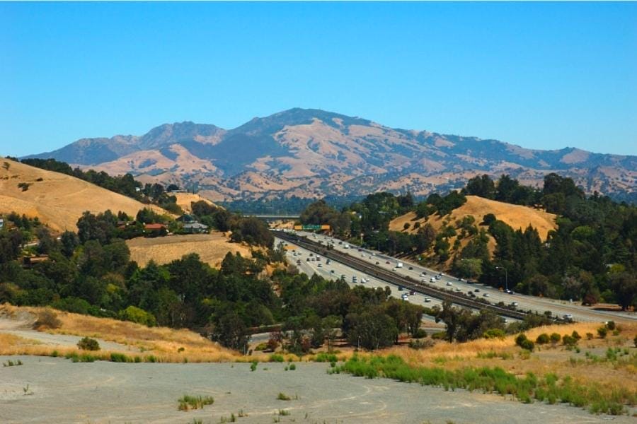 Wide view of the Mount Diablo foregrounded by a wide roads and smaller hills
