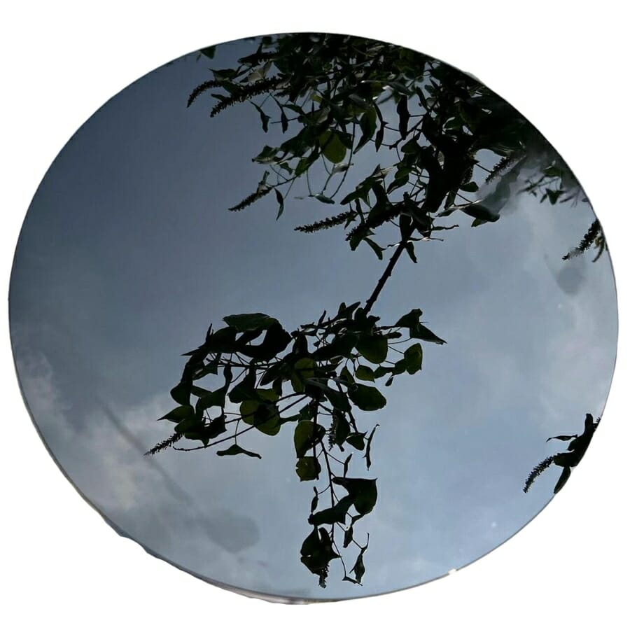 A polished obsidian mirror reflecting the trees and sky
