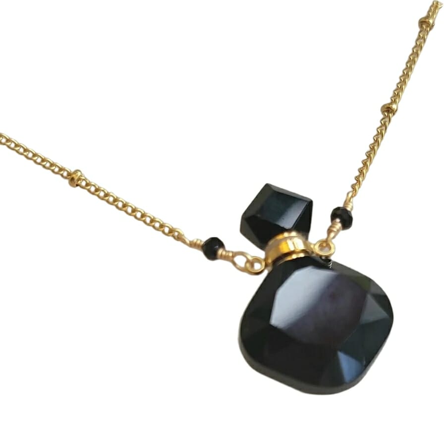 A dainty obsidian necklace shaped like a perfume bottle
