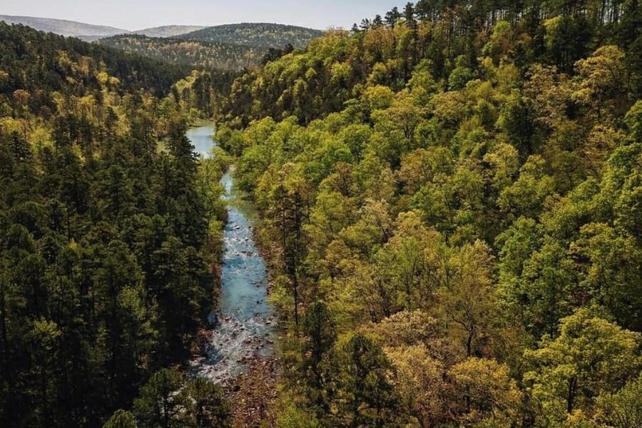 A picturesque aerial view of the Ouachita Mountains with a flowing river and forests of trees