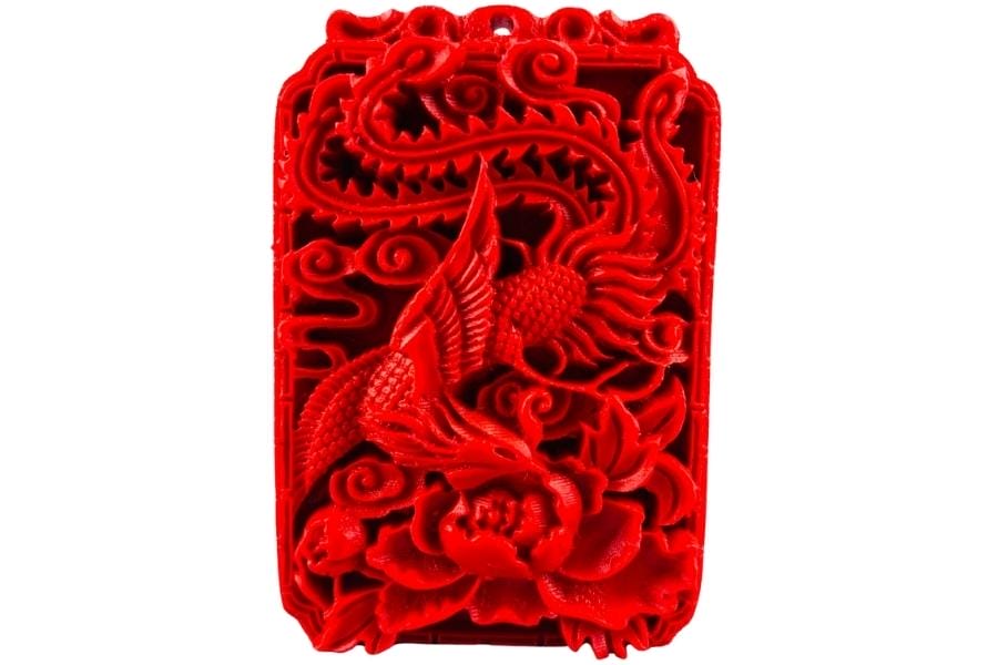 A pendant made out of vibrant red cinnabar and carved with a phoenix