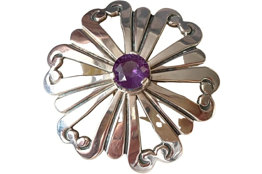 An intricate silver brooch with a purple alexandrite as center stone