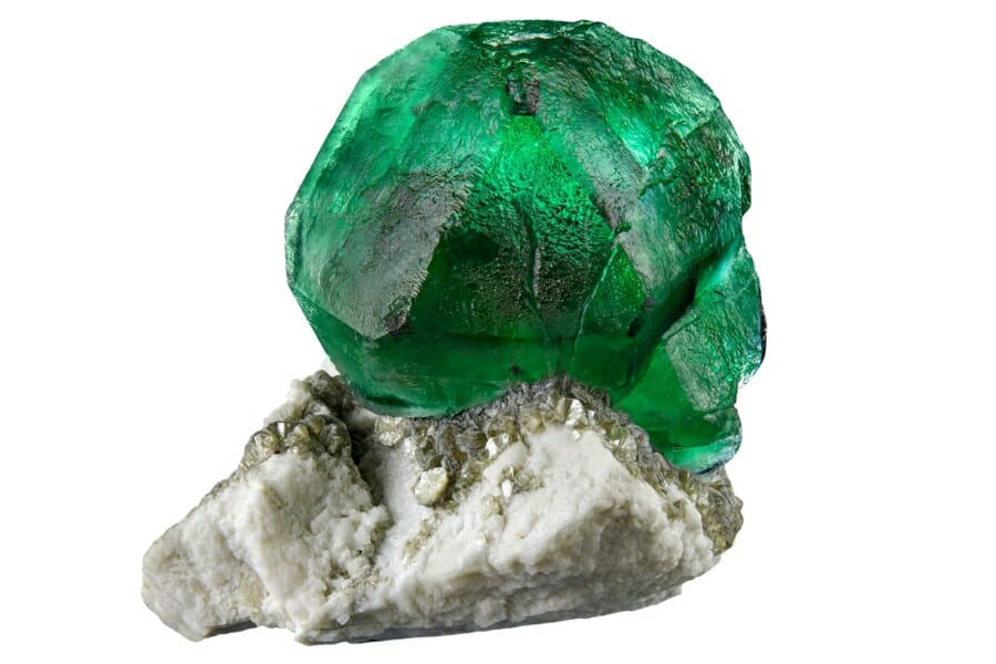 A gorgeous dome-like emerald specimen sitting on top of another mineral