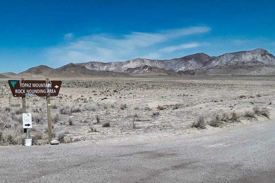 A signage pointing to the Topaz Mountain rockhounding area with the actual mountain on the background