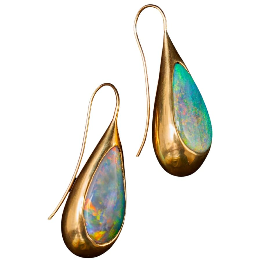 A pair of opal teardrop earrings showing different intensities, patterns, and shades of play-of-color