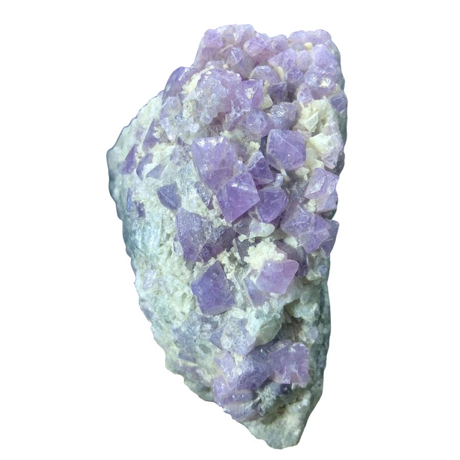 rough purple spinel crystals on a rock