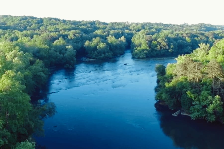 Aerial view of the wide span of Chattahoochee River surrounded by thick trees