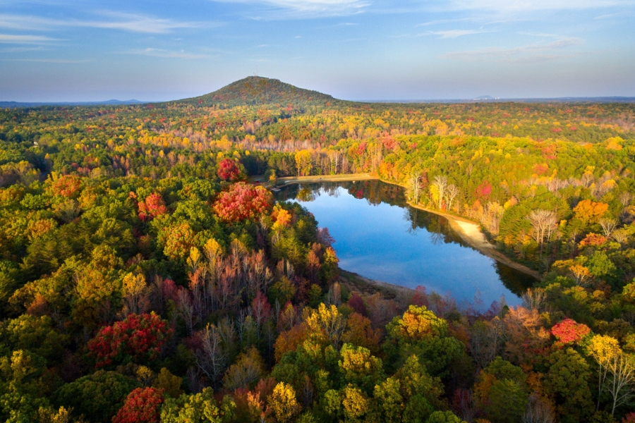 An aerial view of the vast landscape at Crowders Mountain with lush vibrant trees and a lake in the middle