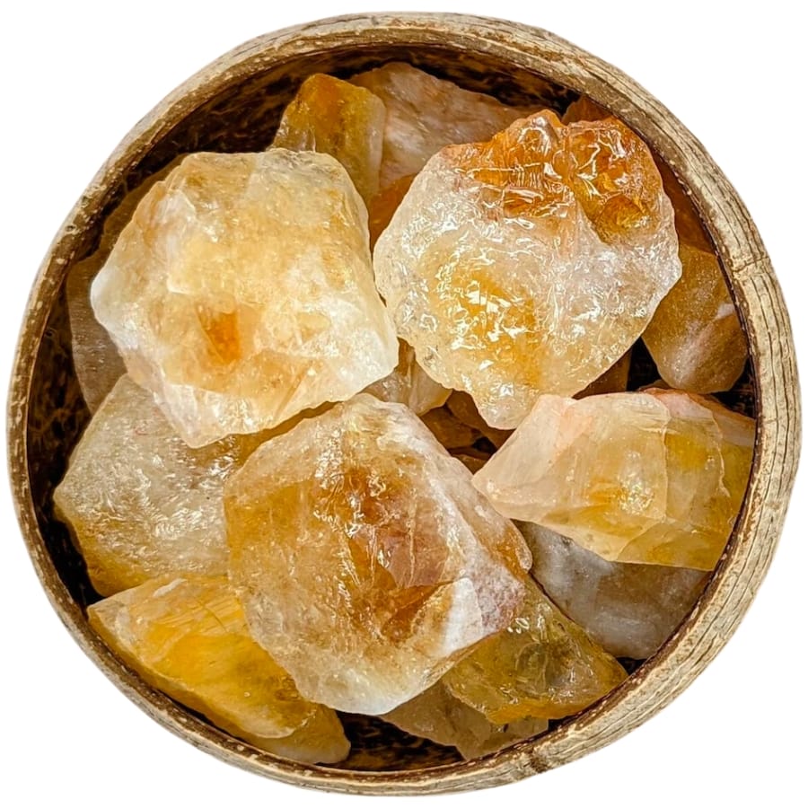 Pieces of raw citrines with varied intensities of yellow on a wooden bowl