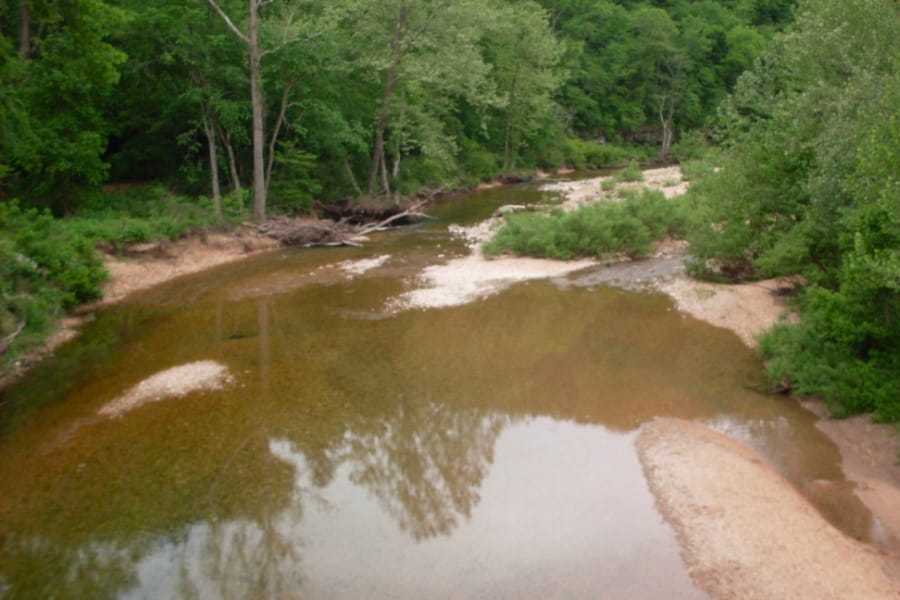 Aerial view of the shallow waters of Indian Creek surrounded with lush trees