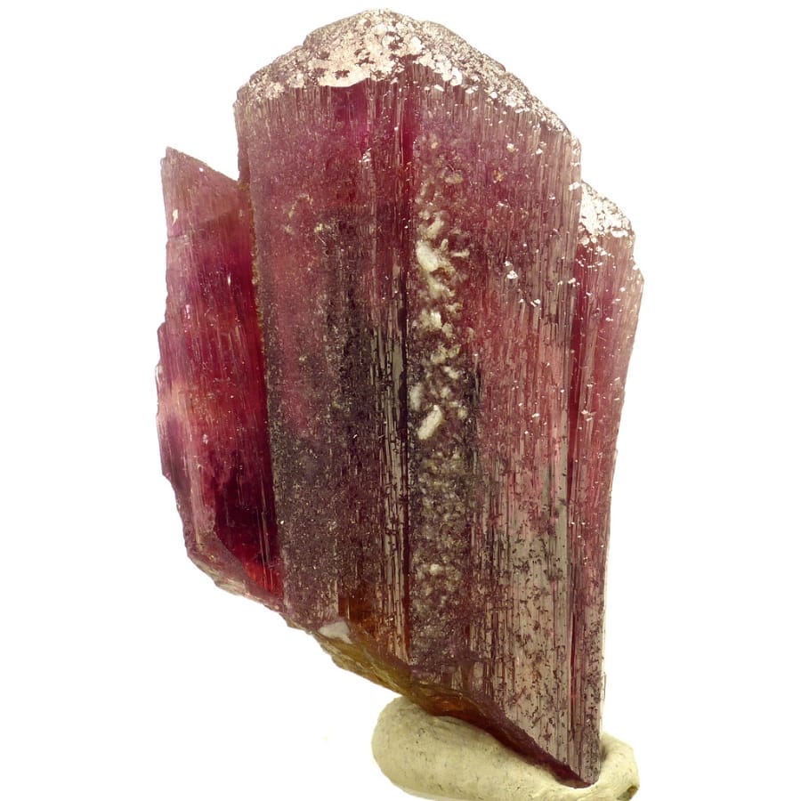 An elegant red tourmaline crystal with flecks of gold on it