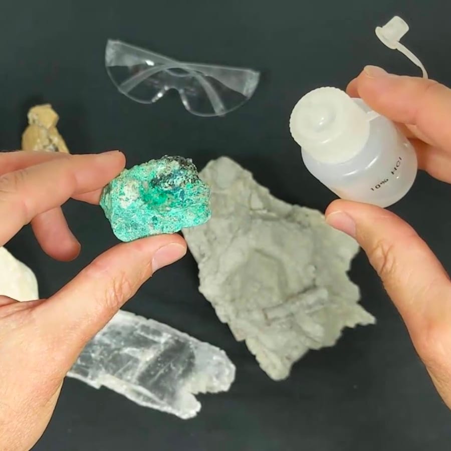 A specimen held on one hand and an acid held on the other for an acid test