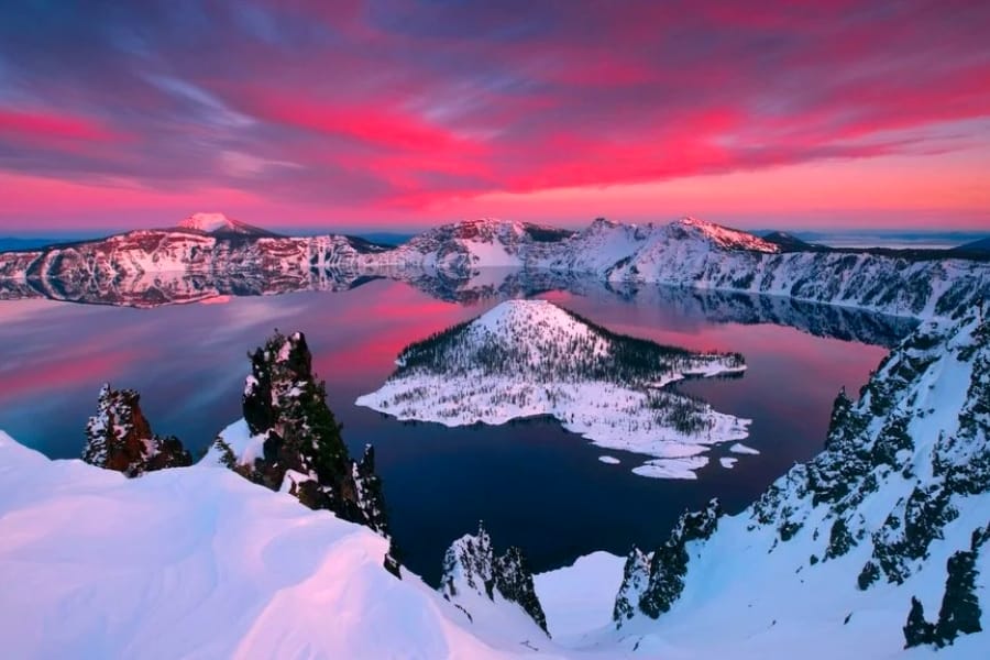 Stunning view of the caldera at the Crater Lake National Park covered with snow under pinkish skies