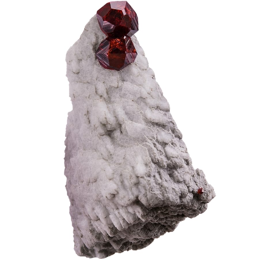 Two maroon-colored spessartine garnets perched on a crystallized white feldspar matrix