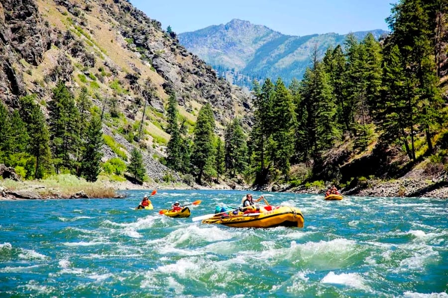 Picturesque view of the Salmon River with numerous visitors paddling over float boats