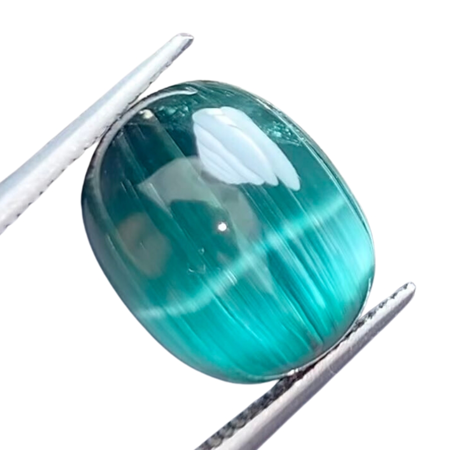 A shiny blue-green cat's eye tourmaline cabochon held with a gem tweezer