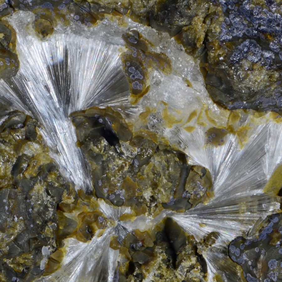 Thin, needle-like strands of white erionite within spaces in a rock