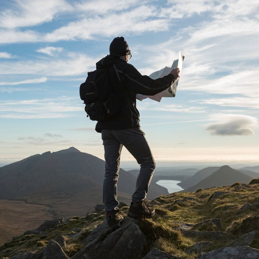 hiker standing on a mountain holding a map