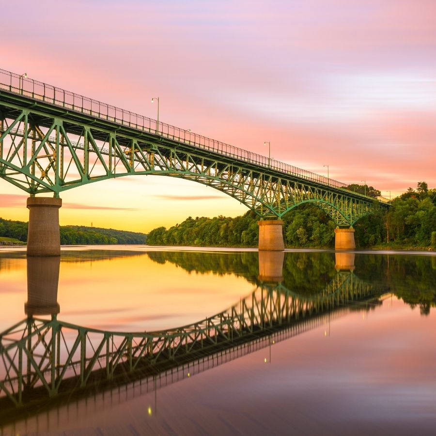 metal bridge over a river against the sunset